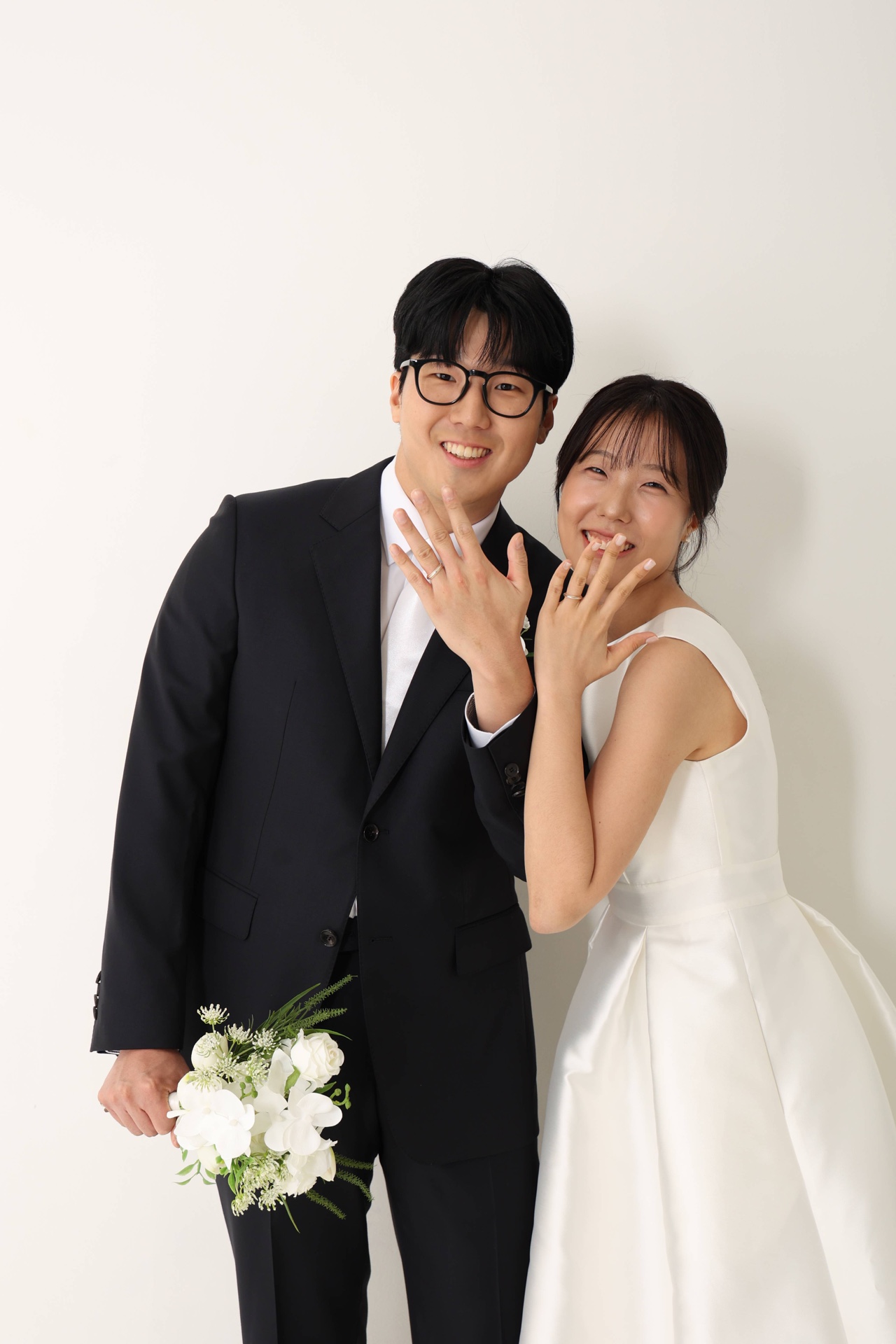 결혼반지를 낀 손을 나란히 들어 보이는 두 사람